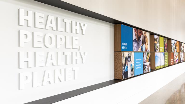Interior shot of a building wall with photos and a sign that reads: Healthy People, Healthy Planet