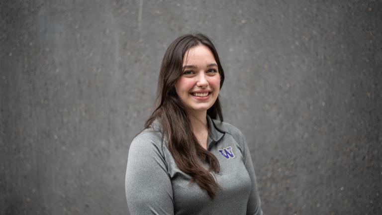 Belen Salguero smiles standing in front of a slate-colored wall.