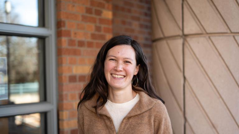 Marissa Childs stands smiling in front of a campus building.