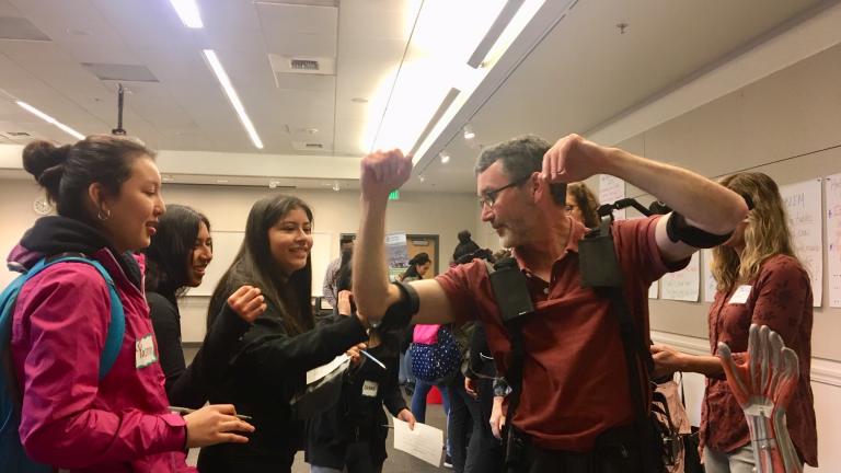 A group of students look at exoskeleton technology worn by a state Department of Labor & Industries employee.