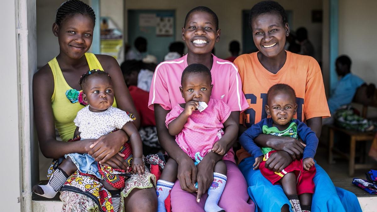 Three Kenyan moms sit with their babies on their laps.