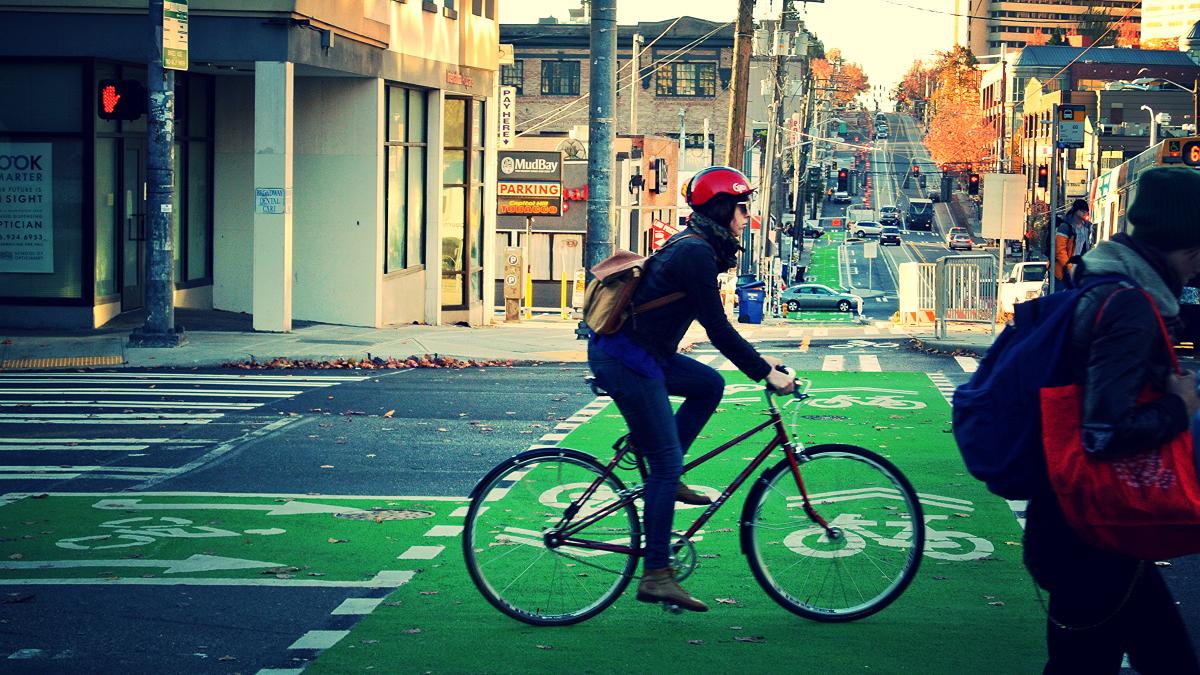 A person bicycles in a protected bike lane marked on the street in Seattle.