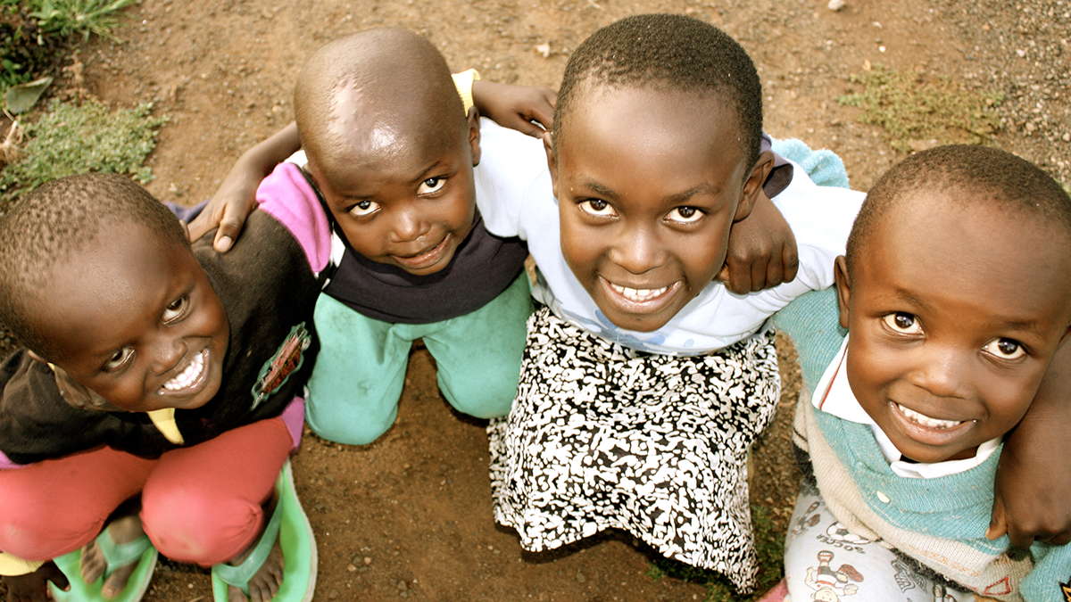 Four smiling children look up at the camera.