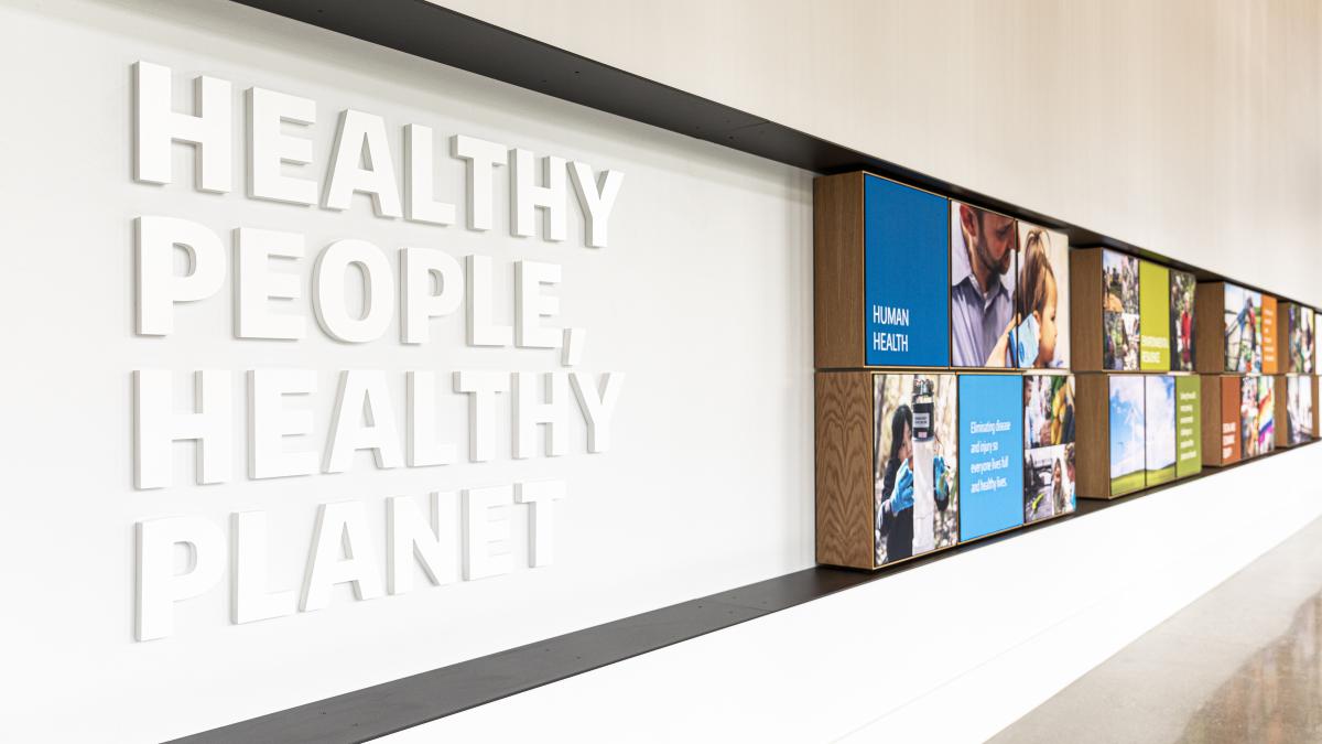 Interior shot of a building wall with photos and a sign that reads: Healthy People, Healthy Planet