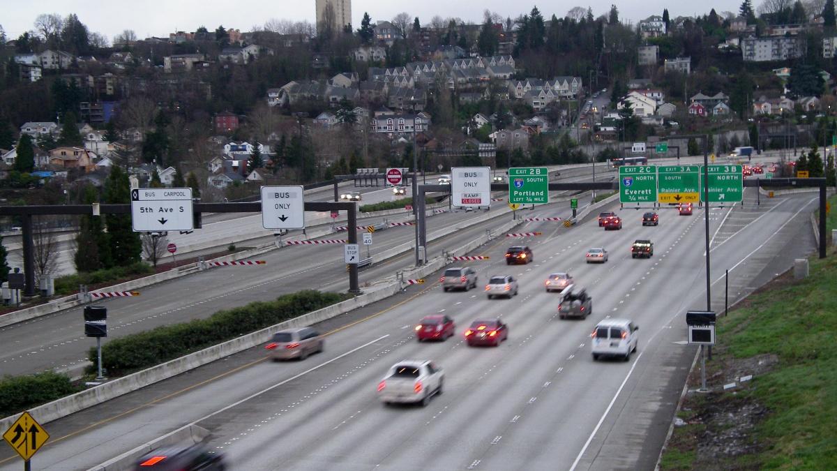 Cars drive along highway I-5 in Seattle with the houses and buildings of Beacon Hill in the background.