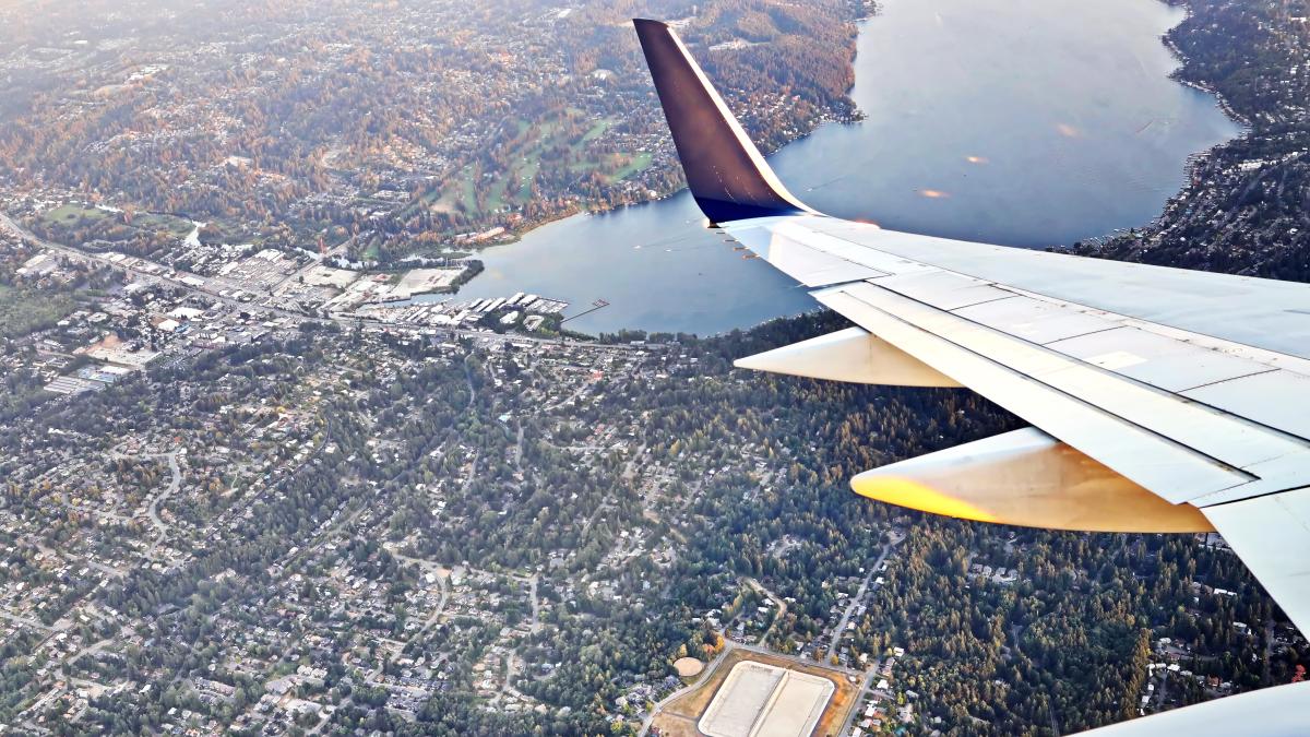 Aerial view shows wing of an airplane flying over a residential neighborhood