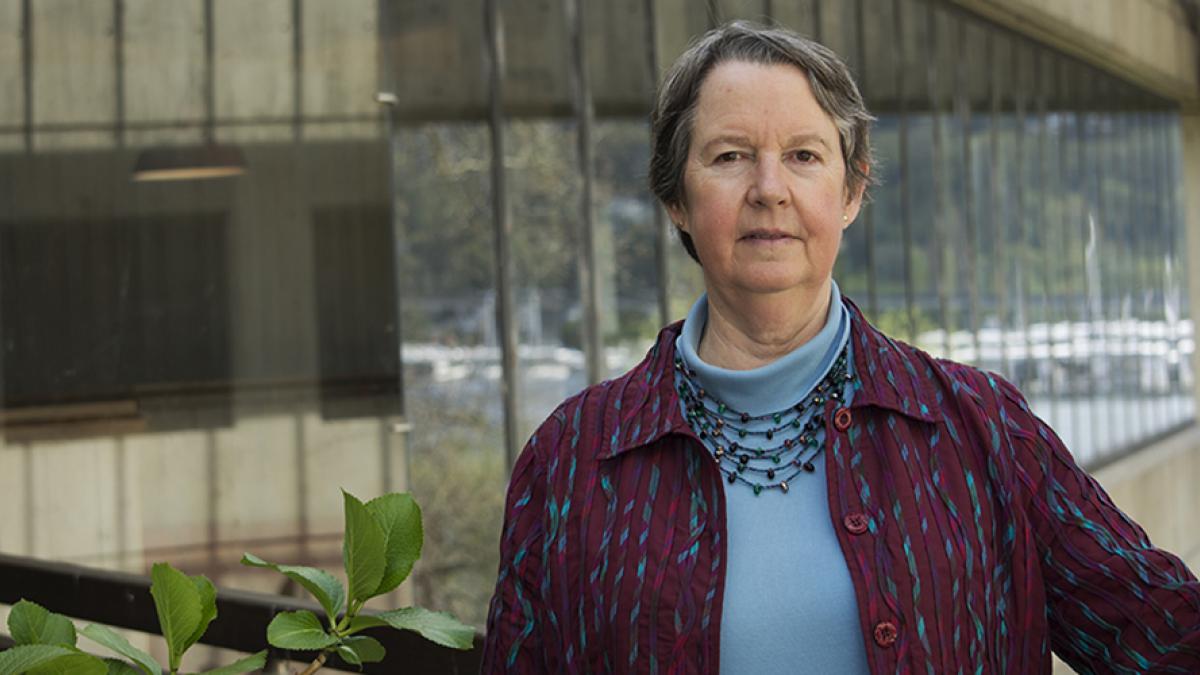 Professor Lianne Sheppard stands outside a University of Washington building next to a green plant.