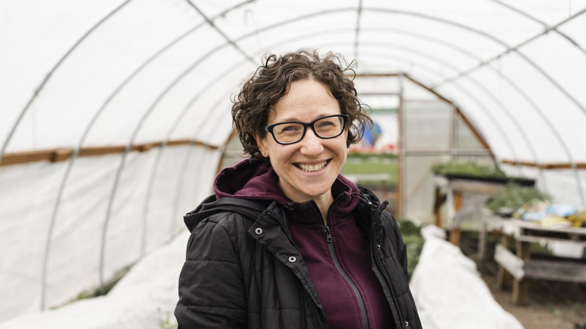 Portrait of DEOHS Lecturer Yona Sipos in a greenhouse