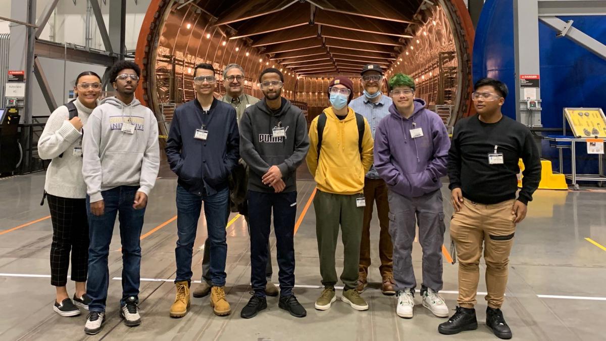 Students from the Brotherhood Initiative stand with DEOHS Professor Martin Cohen and others in front of airplane fuselage at Boeing.