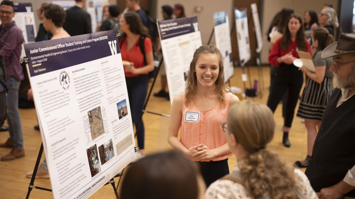 A group of students look at a research poster.