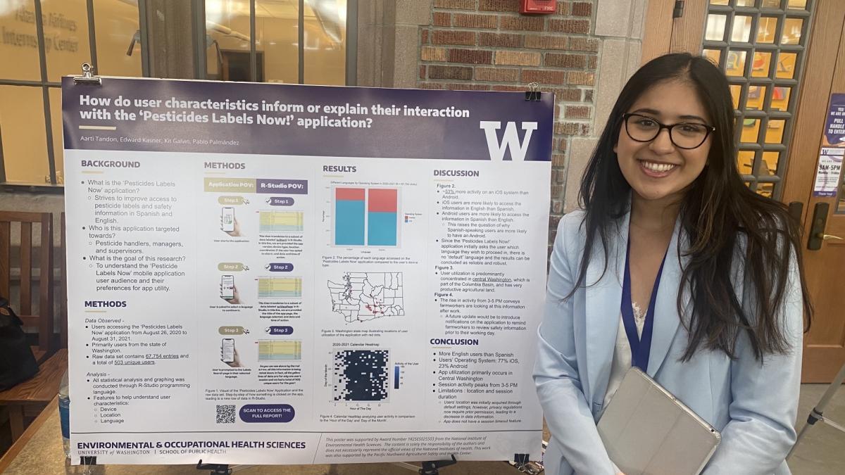 A woman in glasses stands beside a research poster entitled "How do user characteristics inform or explain their interaction with the 'Pesticide Labels Now!' application?