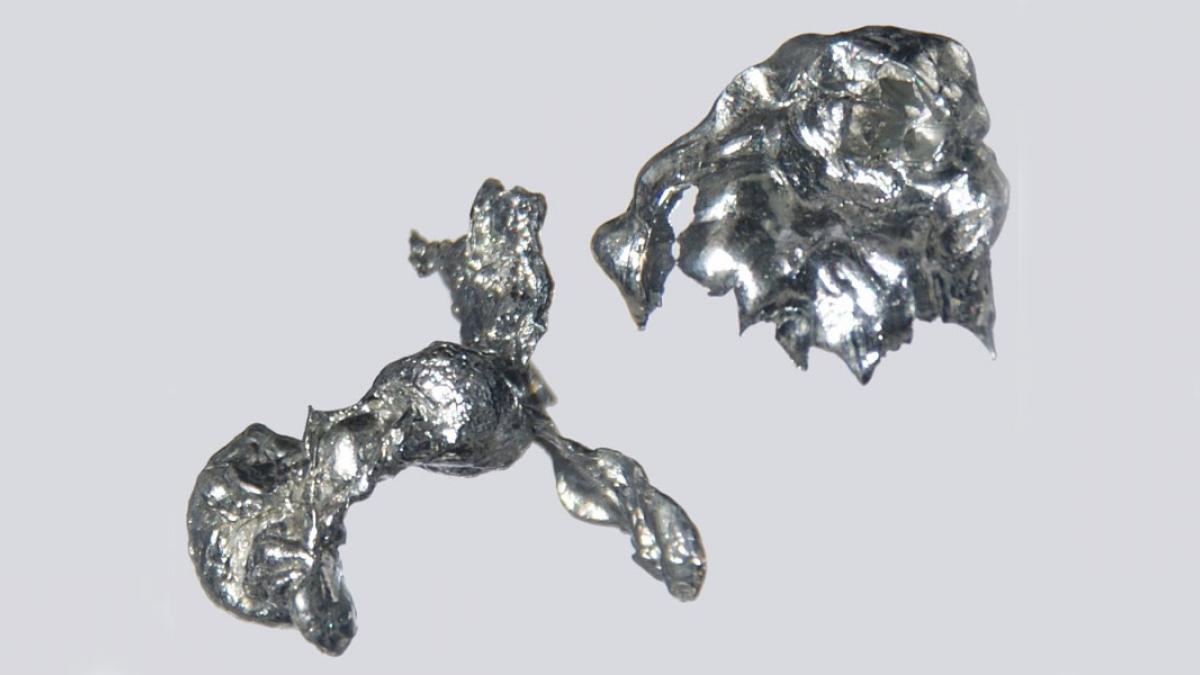 Close-up of the metal cadmium, shown as two irregular bluish-silver shapes on a white background.