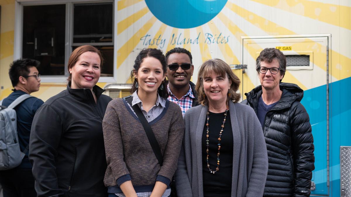 A group of people pose next to a food truck.