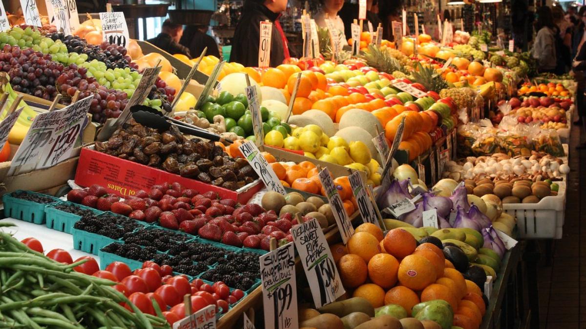 A fruit and vegetable stand at Pike Place Market with purveyors in background.