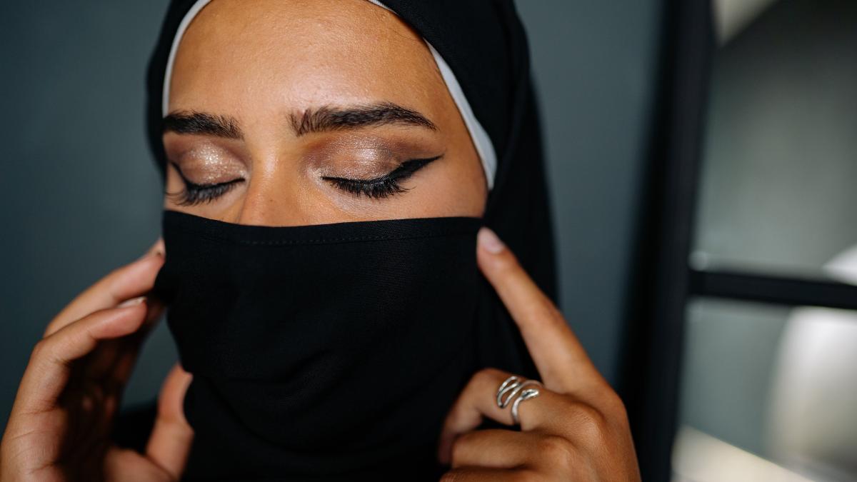 A woman in a hijab with eyes closed wearing traditional eyeliner.
