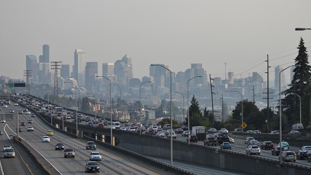 Photo of downtown seattle and interstate 5 with heavy traffic.  A haze of pollution obscures the buildings of downtown.