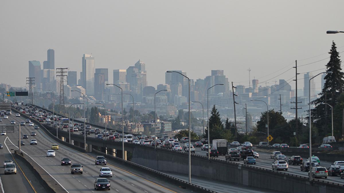 Photo of downtown seattle and interstate 5 with heavy traffic. A haze of pollution obscures the buildings of downtown.