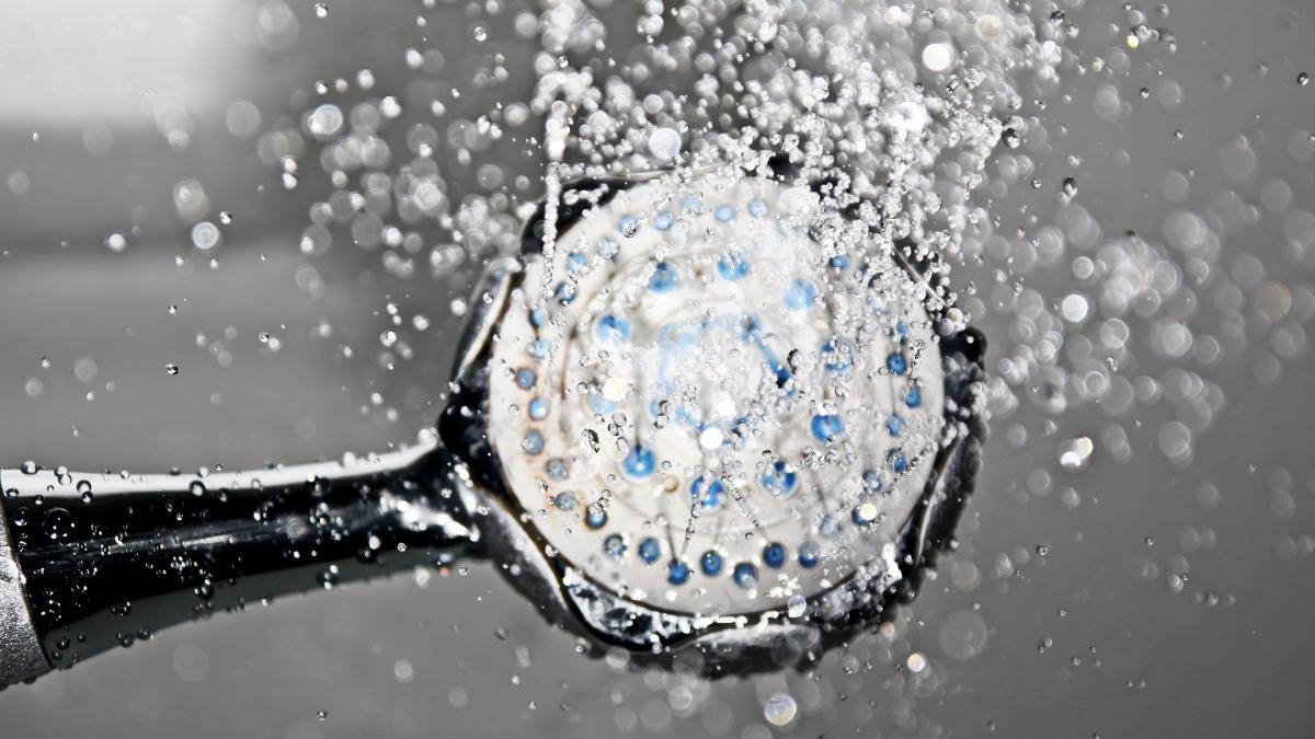 Close-up of a shower faucet and a spray of water.