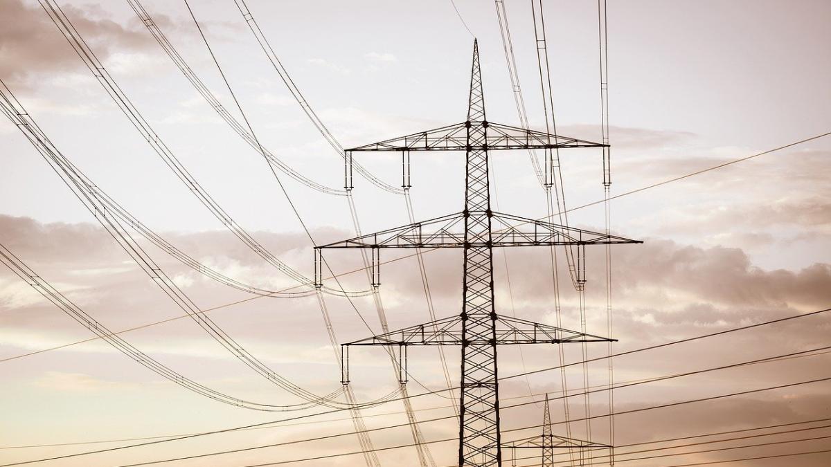 Towers with electrical wires against a cloudy, hazy sky.