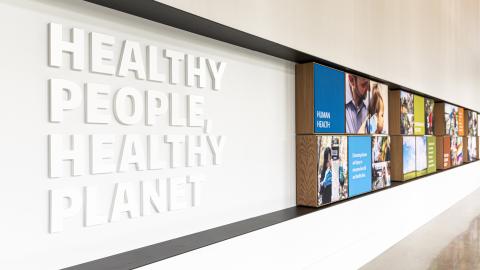 Interior shot of a building wall with photos and a sign that reads: Healthy People, Healthy Planet