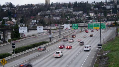 Cars drive along highway I-5 in Seattle with the houses and buildings of Beacon Hill in the background.