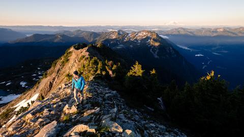 Panoramic photo of person hiking on mountain peaks. Photo by Soren Johnson.