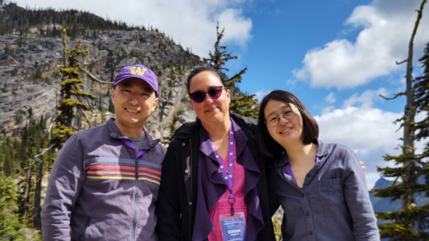 Yijie Geng, Diana Ceballos and Karen Chen stand in front of a mountain slope and trees.