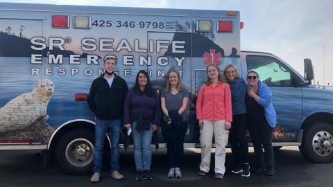 Six people stand in front of an ambulance with a seal painted on the side and text "SR3 Sealife Emergency Response Unit."