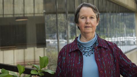 Professor Lianne Sheppard stands outside a University of Washington building next to a green plant.