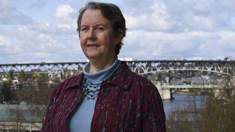 portrait of Lianne Sheppard standing outside.  A bridge with vehicles is in the background.  Photo by Sarah Fish.