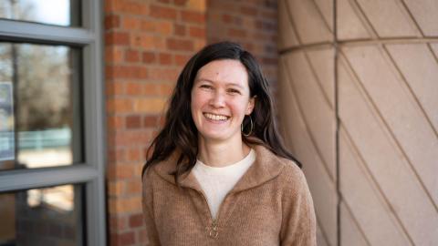 Marissa Childs stands smiling in front of a campus building.