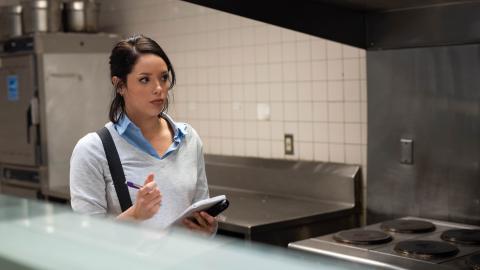 Marissa working in a cafeteria taking food safety notes