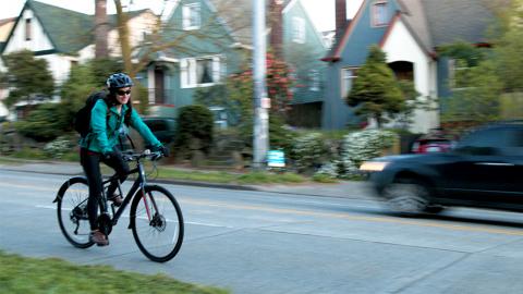 Rachel Shaffer bikes on a street in front of houses. Photo by Alex Kritchevsky.