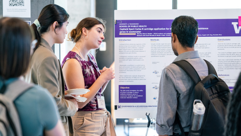 Several students stand around a poster during the School of Public Health Undergraduate Symposium.
