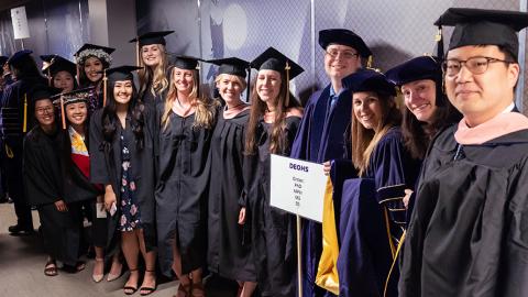 DEOHS Students pose for a photo in the hallway before entering the stadium where the SPH graduation ceremony will take place.