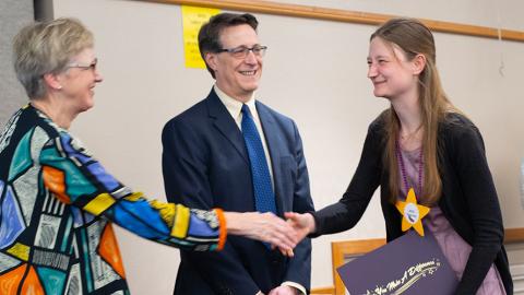 Meagan Jackson, a DEOHS award recipient, shakes hands with Shirley Beresford while receiving her award. Joel Kaufman watches.