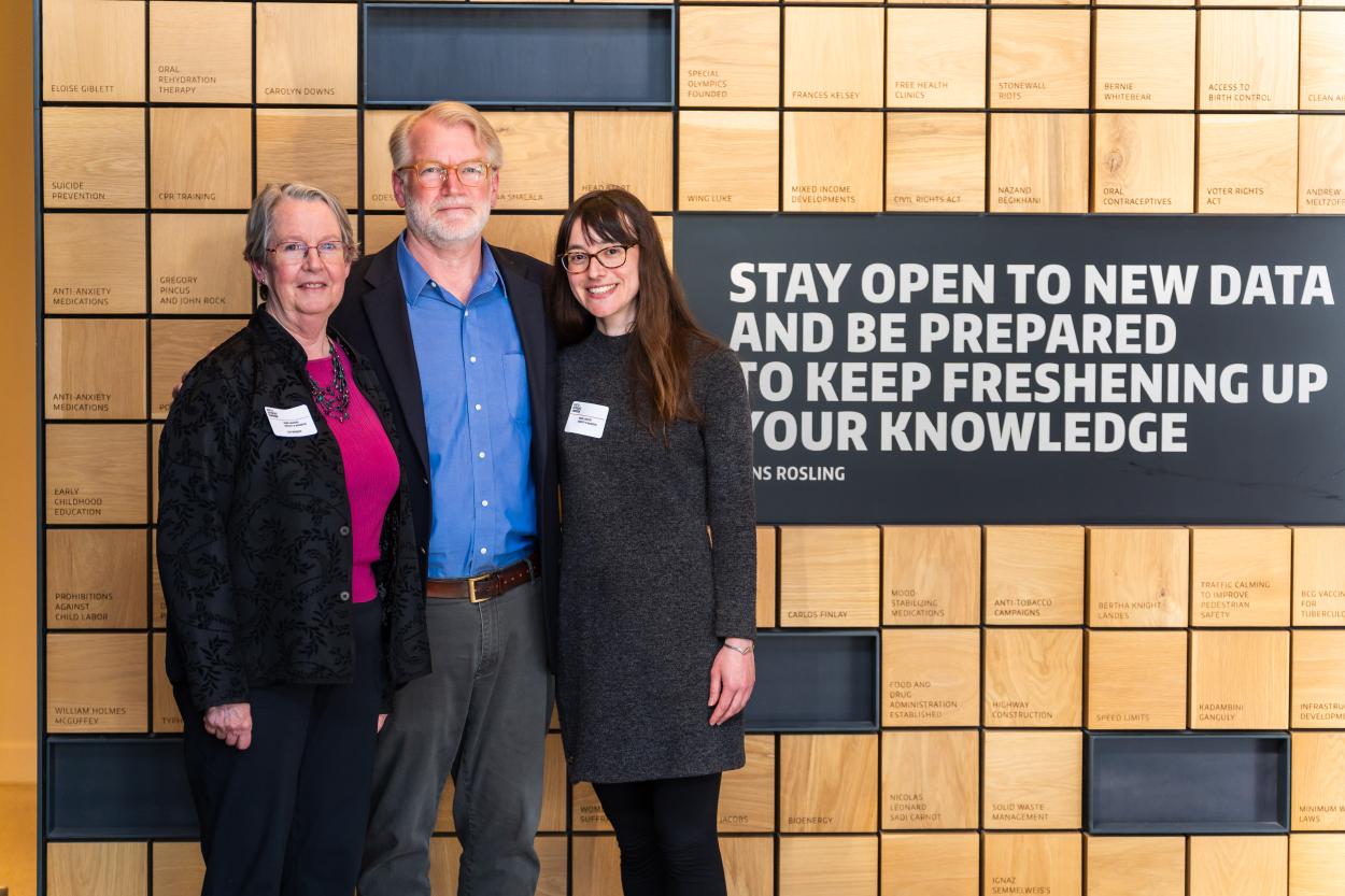 Lianne Sheppard, Bruce Lanphear and Rachel Shaffer stand in front of a sign reading "Stay open to new data and be prepared to keep freshening up your knowledge. - Hans Rosling."