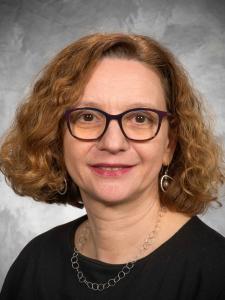 Dr Guizzetti, a middle-aged white woman with curly red hair and dark framed glasses