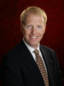 Dr Tubby, a middle-aged white man with short red hair wearing a suit