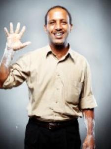 Dr Mazengia, a young black man waving with chalky hands