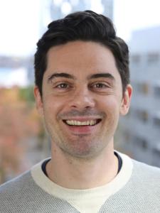 Man with short dark hair wearing gray sweater
