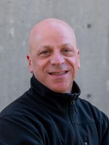 Bald man wearing black zip-up pullover