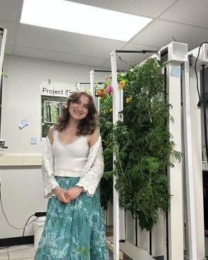 Angelina Durbin stands smiling next to flowers growing at the UW Indoor Farm.