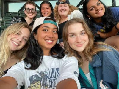 Do and six other students smile together at a baseball game.