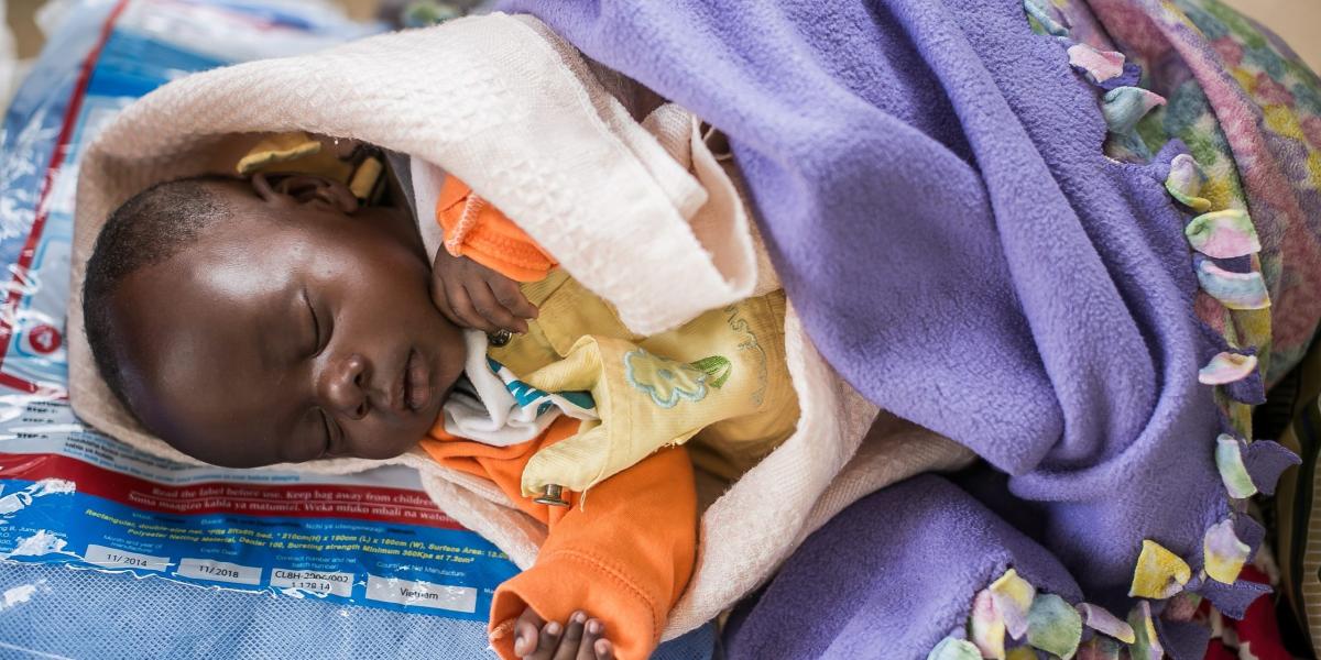 Sleeping Kenyan baby wrapped in blankets