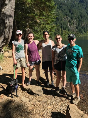 Five hikers linking arms in front of a lake.