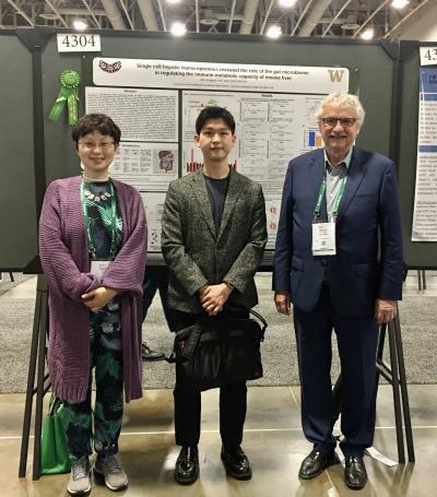 Three people pose in front of a research poster.