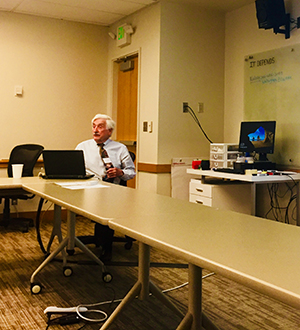 Dr. David Carpenter sits with his laptop during his presentation.