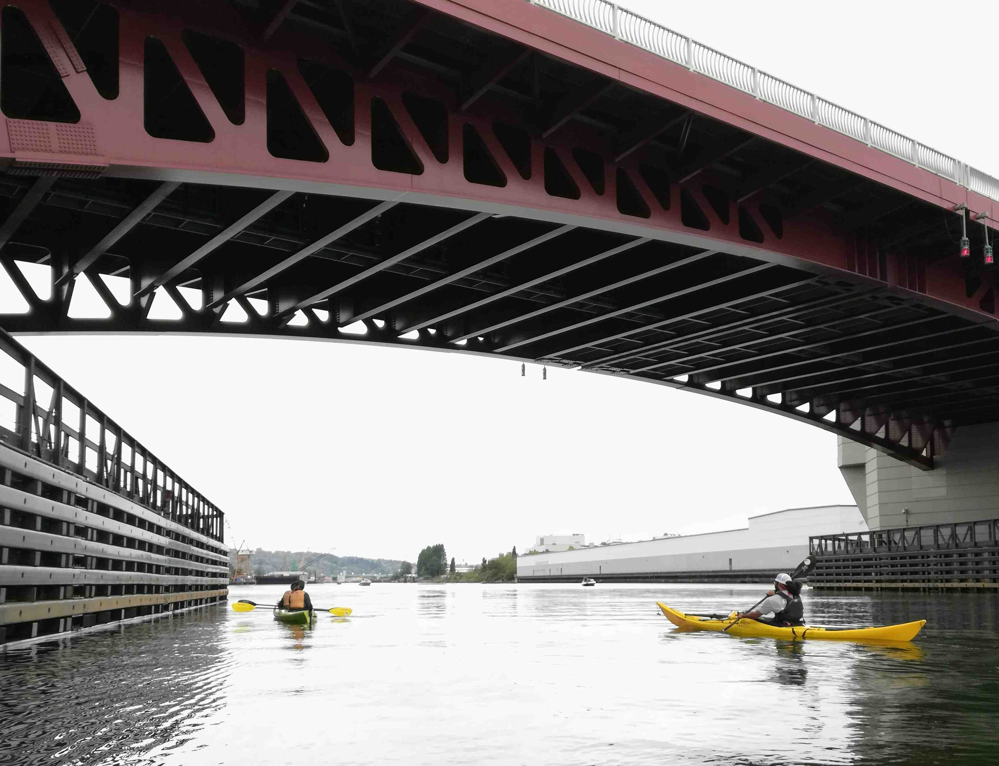 kayakers pass under bridge