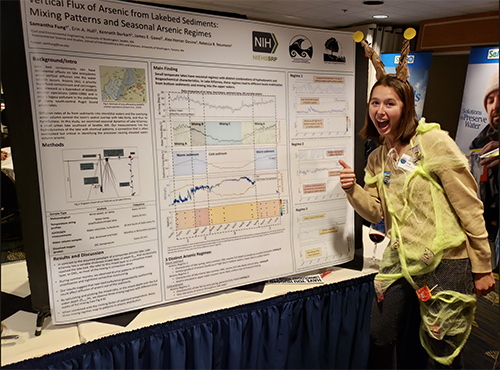 Samantha Fung stands in front of a poster dressed as a snail in a food web